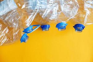 a lot of plastic empty rumpled used bottles on a yellow background. waste and pollution concept photo