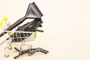 various hairdressing tools with shopping cart on a beige background. beauty salon concept photo