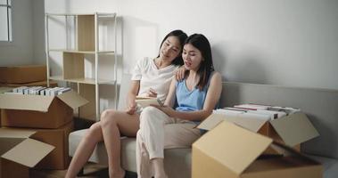 Footage of Asian young women discussing ideas about interior design of the new home while sitting on couch. Moving and lifestyle concepts. video