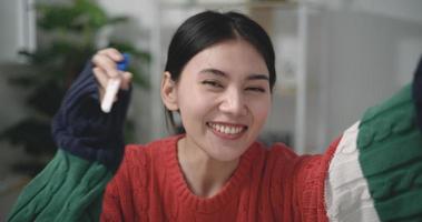 metraggio avvicinamento di contento asiatico giovane donna guardare a gravidanza test nel felicità mentre seduta su divano a il vivente camera. gravidanza o famiglia concetti. video