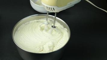 Chef is making cream cake using electric portable hand mixer machine, home bakery cooking concept video