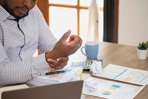 An American businessman with black skin in Africa feels uncomfortable at work and wrist pain is caused by the accumulated stress from failing to complete the job. and the body rests a little. photo