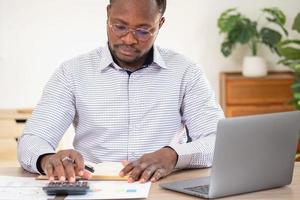 African black businessman sitting doing a financial report and studying annual profit analysis An accountant checking the financial status of the company is in the office. photo