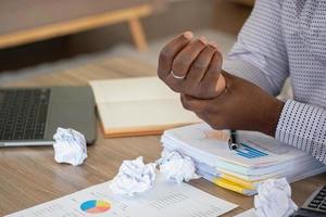 An American businessman with black skin in Africa feels uncomfortable at work and wrist pain is caused by the accumulated stress from failing to complete the job. and the body rests a little. photo