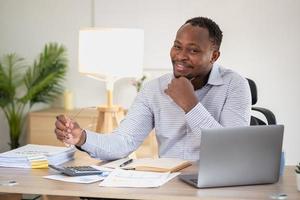 African black businessman sitting doing a financial report and studying annual profit analysis An accountant checking the financial status of the company is in the office. photo