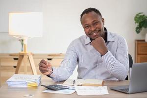 African American businessman smiling relaxed and crossed arms after analysis and research at home office photo