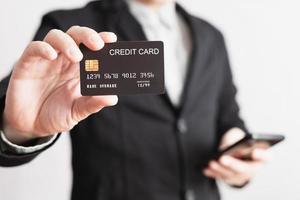 businessman showing a mock-up credit card for shopping to make payment and smartphone.half body. Concept for banner, purchase, commerce, financial, card, money, using technology. selective focus. photo