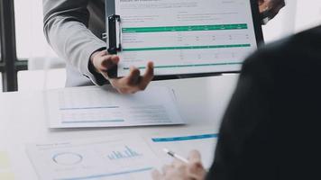 Financial analysts analyze business financial reports on a digital tablet planning investment project during a discussion at a meeting of corporate showing the results of their successful teamwork. video