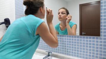 jolie femme appliquant noir mascara pour cils maquillage dans de face de salle de bains miroir video