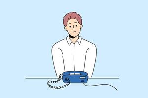 Unhappy man sit at desk look at landline phone waiting for someone call. Frustrated guy awaiting ring looking at corded telephone. Vector illustration.