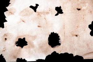 Several burnt holes in a sheet of paper photo