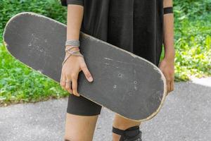 Close-up of an unrecognizable young skateboarder holding a board photo