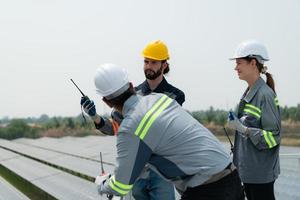 On the rooftop of a large solar energy storage station building A team of electric power engineers inspecting solar panels that have been installed on hundreds of acres of fields. photo