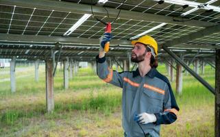 Electrical engineers are inspecting and maintaining solar cells at a solar cell panel in the middle of a hundred acres of grass. photo