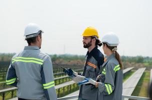 On the rooftop of a large solar energy storage station building A team of electric power engineers inspecting solar panels that have been installed on hundreds of acres of fields. photo