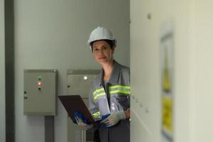 Young female engineer inspecting system of a large solar energy storage station in the middle of the field of solar cells on an area of hundreds of acres photo