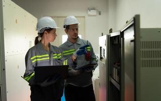 Electric power engineering team inspecting system of a large solar energy storage station in the middle of the field of solar cells on an area of hundreds of acres photo