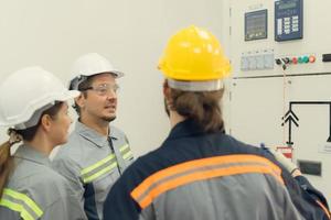 Electric power engineering team inspecting system of a large solar energy storage station in the middle of the field of solar cells on an area of hundreds of acres photo