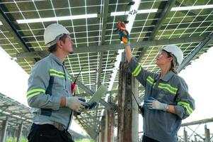 A team of electrical engineers is inspecting and maintaining solar panels at a solar panel site in the middle of a hundred acre field. photo