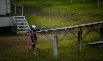 An electrical engineer is inspecting a solar cell that has been used for some time, installed on a field hundred acres of grass. photo