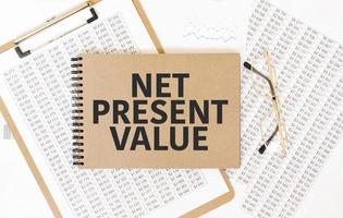 Craft colour notepad with text net present value. Notepad with eyeglasses and text documents. Business concept photo