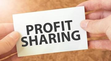 profit sharing word inscription on white card paper sheet in hands of a businessman. recap concept. red and white paper photo