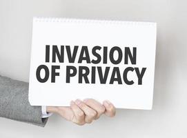 Businessman holding a card with text invasion of privacy photo