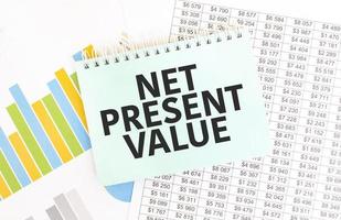 Green notepad on financial documentation. Text net present value. Business concept photo