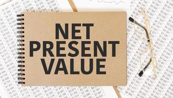 Craft colour notepad with text net present value Notepad with eyeglasses and text documents. Business concept photo