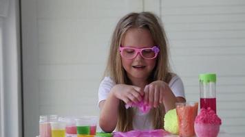 A little girl with glasses is played with a homemade pink slime. Kids hands playing slime toy. Making slime. Copyspace. video