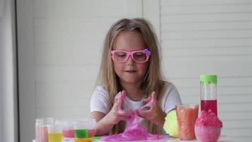 A little girl with glasses is played with a homemade pink slime. Kids hands playing slime toy. Making slime. Copyspace. video