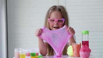 A little girl with glasses is played with a homemade pink slime. Kids hands playing slime toy. Making slime. Copyspace. video