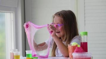 A little girl with glasses is played with a homemade pink slime. Kids hands playing slime toy. Making slime. Copyspace. video