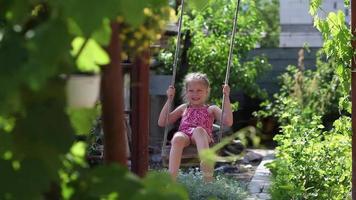 allegro ragazza equitazione nel il cortile di il Casa su un' improvvisato swing video