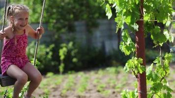 Cheerful girl riding in the courtyard of the house on a makeshift swing video