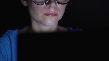 Woman in glasses looking on the monitor and surfing Internet at night. The monitor screen is reflected in the glasses video