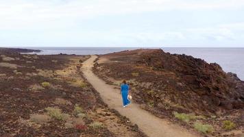 se från de höjd av kvinna i en skön blå klänning och hatt står på topp av en berg i en bevarande område på de stränder av de atlanten hav. teneriffa, kanariefågel öar, Spanien video