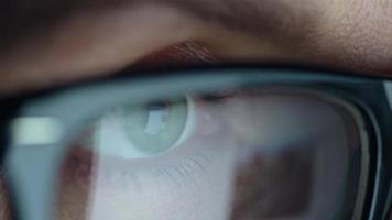Woman in glasses looking on the monitor and surfing Internet at night. The monitor screen is reflected in the glasses video