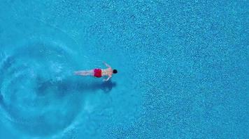 Aerial view of man in red shorts swims in the pool video