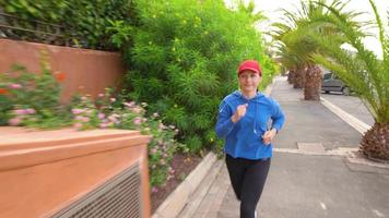 Woman jogging along the street among the tropical alley video