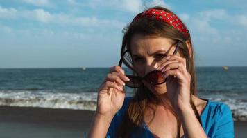 retrato do uma complicado mulher dentro uma lindo azul vestir em uma Preto vulcânico de praia video