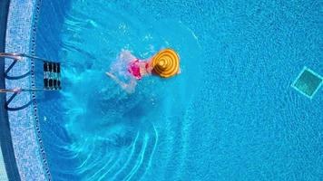 View from the top as a woman in a red swimsuit lying on her back in the pool. Relaxing concept video