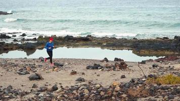 mulher corre ao longo a pedregoso costa do a oceano. saudável ativo estilo de vida video