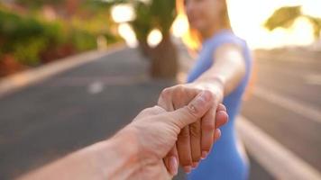 Follow me - happy young woman pulling guy's hand - hand in hand running on a bright sunny day. Slow motion video