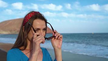 Portrait of a tricky woman in a beautiful blue dress on a black volcanic beach video