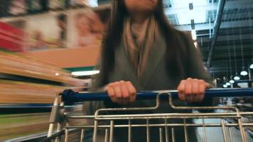 Tempo lapso do a compras carrinho comovente entre vários corredores e seção dentro a grande supermercado. mulher compras dentro uma mercearia loja video