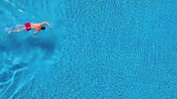 aéreo ver de hombre en rojo pantalones cortos nada en el piscina video