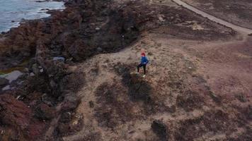 Aerial view of woman runs along the oceanfront nature reserve at sunrise. Healthy active lifestyle video