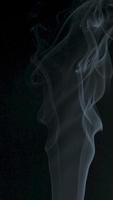 Slow motion vertical video of white smoke, fog, mist, vapor on a black background.