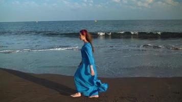 portrait de une femme dans une magnifique bleu robe sur une noir volcanique plage video